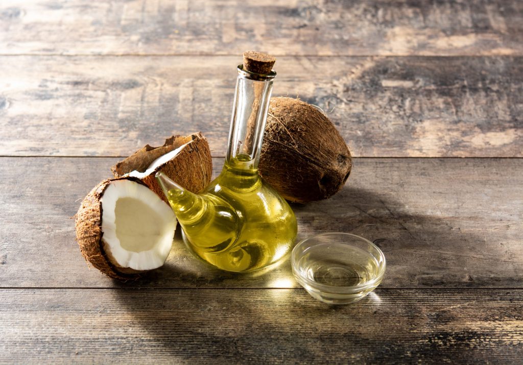 ثمار جوز الهند وبجانبها قارورة تحتوي زيت جوز الهند