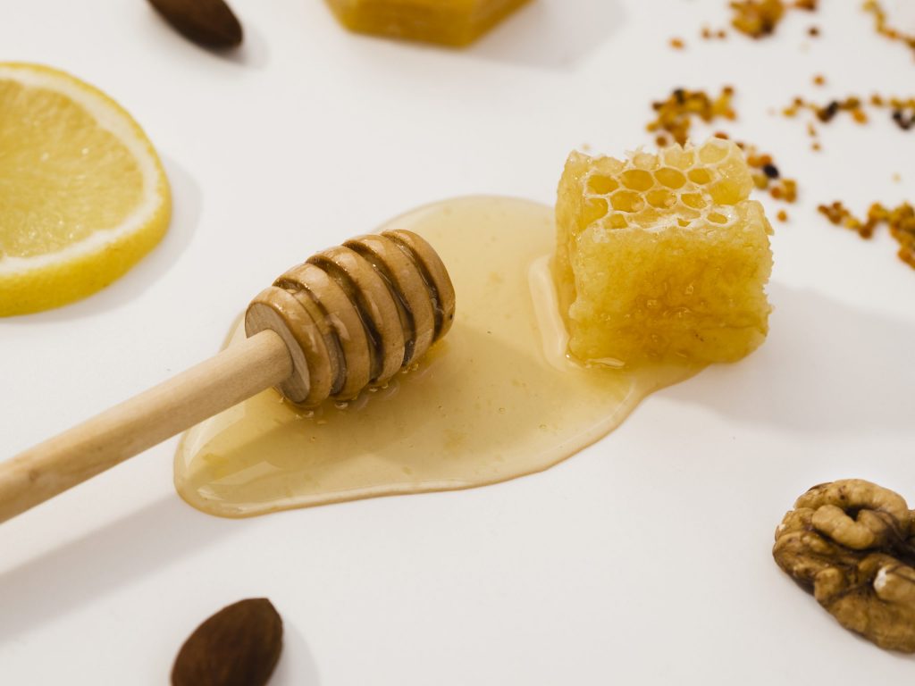 صورة مكعب من العسل وملعقة يسيل منها العسل مشكلاً رقعة عسل